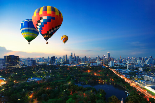 Hot-air-balloons-fly-over-cityscape-at-sunset-background.jpeg