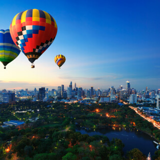 Hot-air-balloons-fly-over-cityscape-at-sunset-background